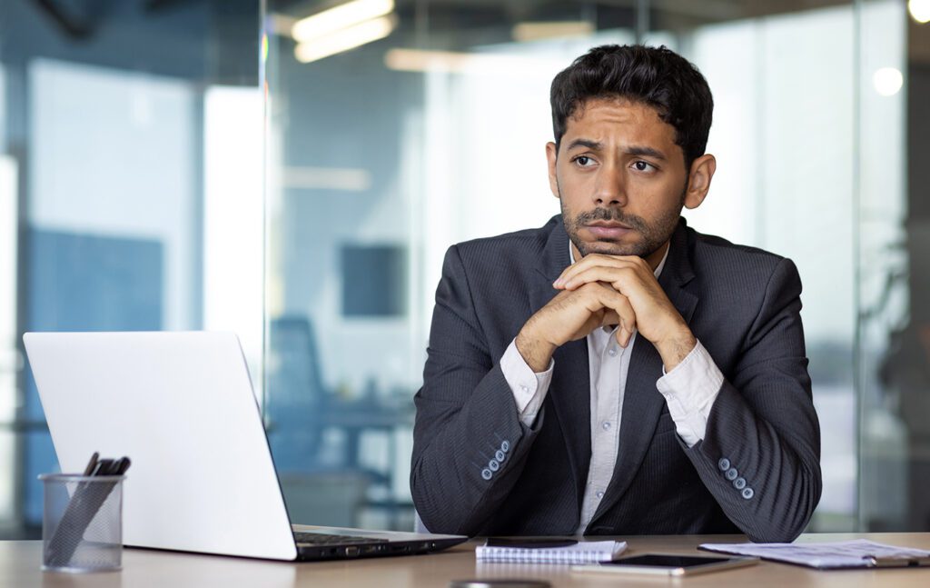 Man sitting at desk appearing anxious.