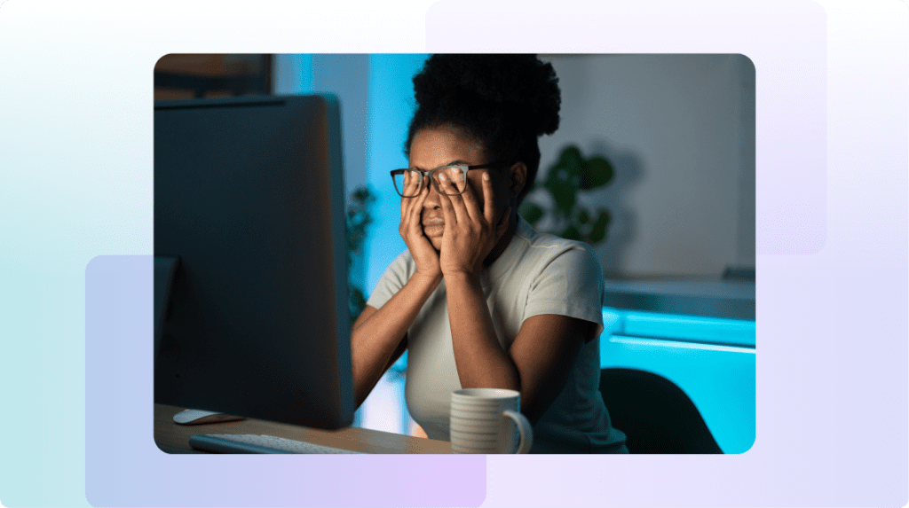 Person sitting at desk with hands covering face, appearing overwhelmed.