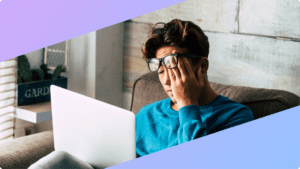 a person at their laptop, rubbing their eyes
