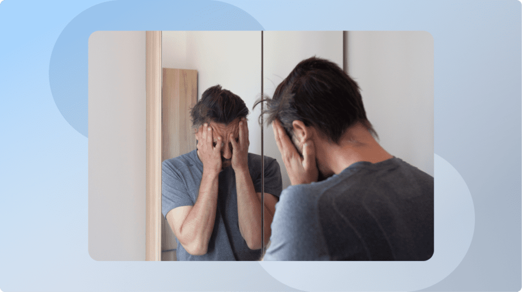 a person standing in front of the mirror, covering their face