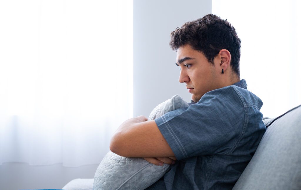 Man hugging cushion in anxiety.