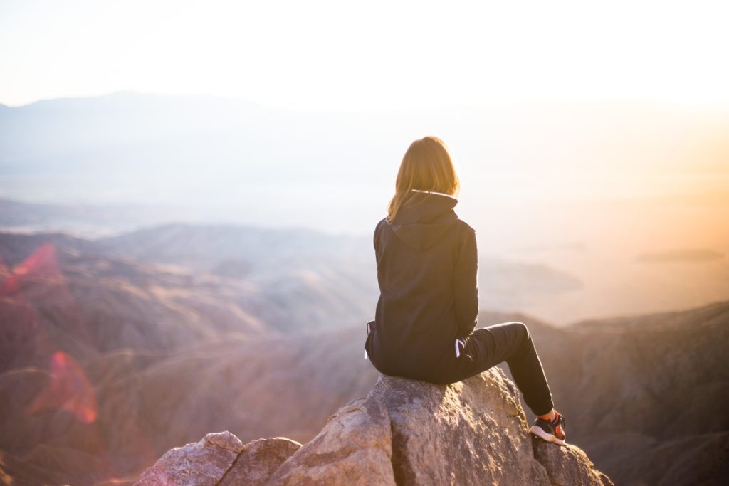 Woman sitting on top of mountain